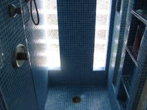 Blue mosaic shower and adjustable glass shelves